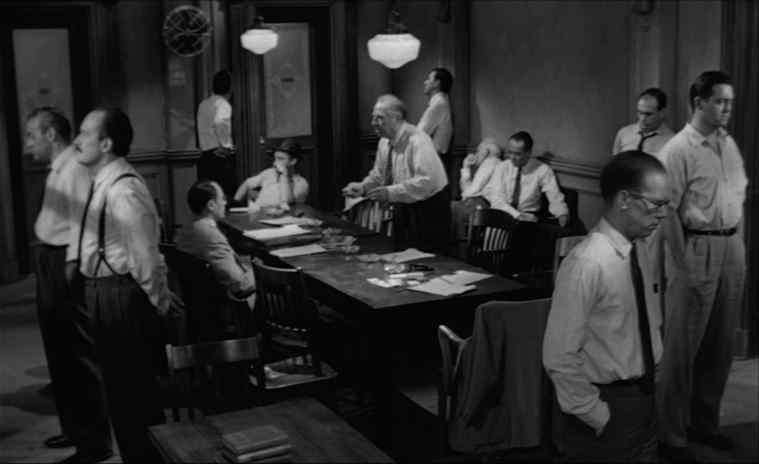 Twelve men in black and white arguing around a table